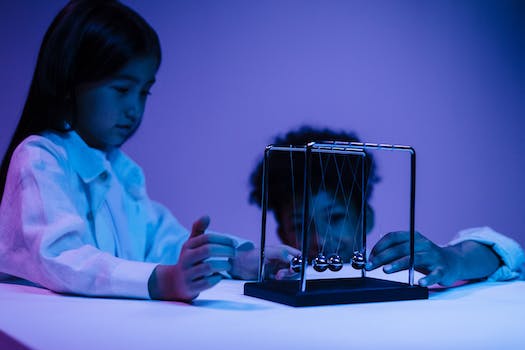 Boy and girl playing with newton s cradle in a blue light