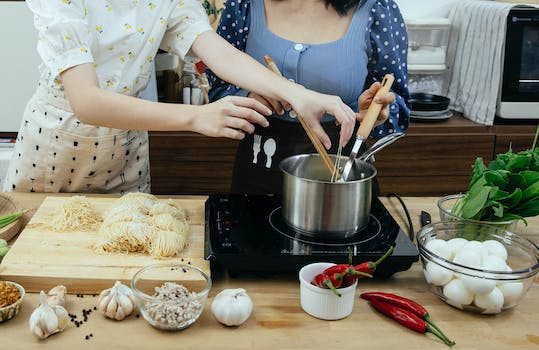 Crop faceless women cooking traditional noodle dish together