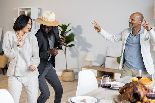 Happy multiethnic friends dancing together near table with dishes