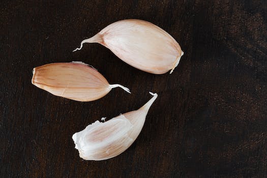 Top view of several cloves of ripe garlic in peel placed on wooden desk during cooking process at home