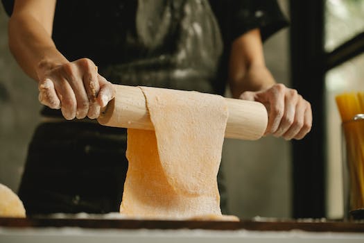 Chef stretching dough on rolling pin for making pasta