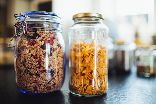 Glass jars with healthy cornflakes and muesli placed on table in kitchen