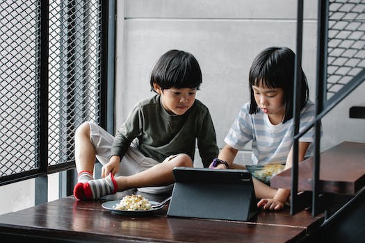 Asian kids watching video on tablet near stairs