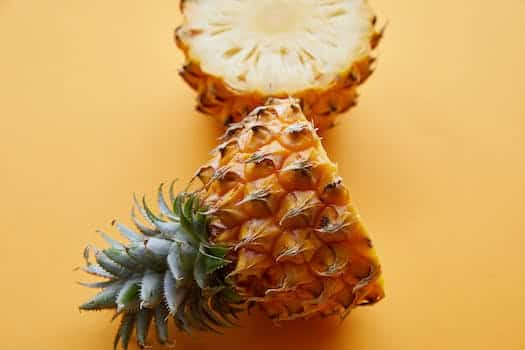 From above of fresh textured half cut pineapple on bright yellow background of studio