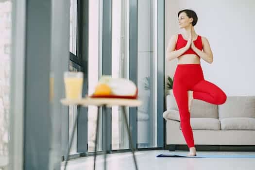 From below of content female in activewear standing on mat in living room while doing yoga exercise and looking away