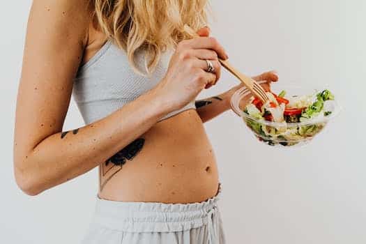 Unrecognizable Blonde Woman Eating Salad from Glass Bowl