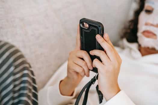 Woman text messaging on smartphone while doing skin care procedure