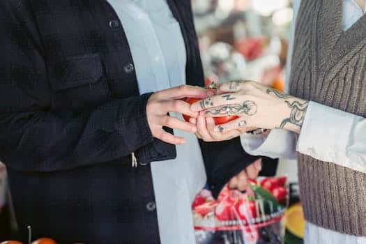 Crop unrecognizable couple in casual clothes choosing fresh ripe tomatoes during shopping in local food market on sunny day
