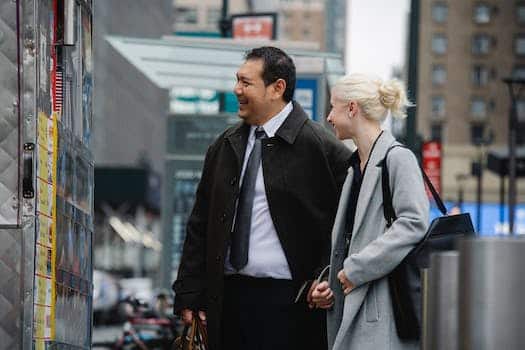 Mature man and woman in business clothes buying food in street van while chatting happily