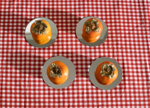Ripe bright orange persimmon placed on plates on checkered tablecloth