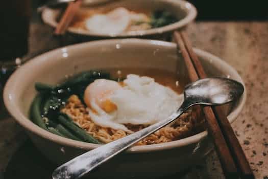 A bowl of noodles with an egg and chopsticks