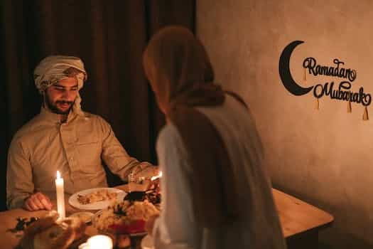 Man in Brown Thobe Sitting Beside Woman in White Hijab
