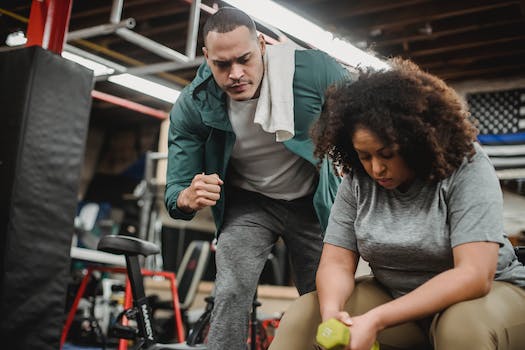 African American trainer working with black female client during training in modern gym