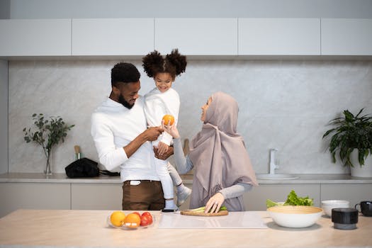 Happy young multiracial family in casual outfits standing near table in kitchen while cooking together at home
