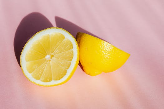 Top view of halves of fresh juicy lemon composed on pink background in sunbeams